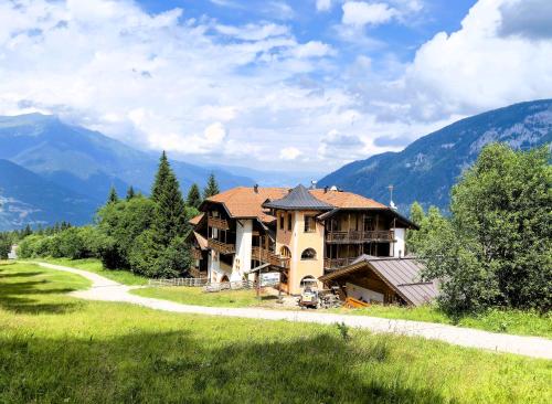 a large house on a hill with mountains in the background at Hotel Dal Bracconiere in Folgarida