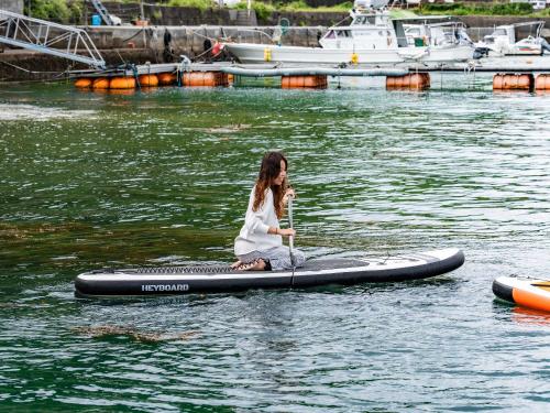 a woman sitting on a paddle board in the water at Calm Lanai Harbor in Nichinan