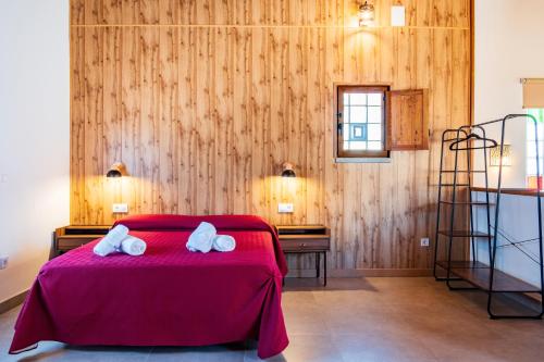 a bedroom with a red bed with two towels on it at Quercus in Navaluenga