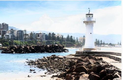 a lighthouse on the shore of a body of water at beach pad in Wollongong