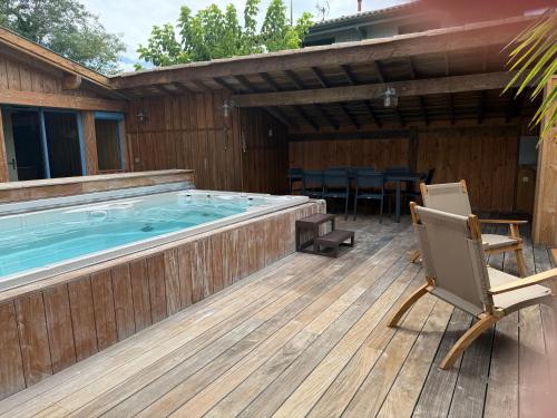 a hot tub on a deck with a chair at Villa JANE vue Bassin in Lège-Cap-Ferret