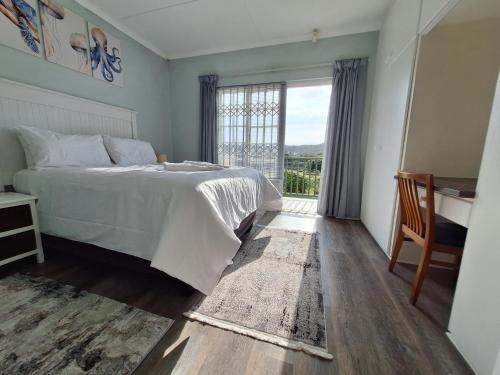 Un dormitorio con una cama y una ventana grande. en Whales Drift Beach Apartment, en Port Alfred