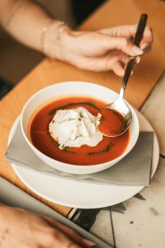 a bowl of soup on a plate with a spoon at Hotel Glemmtalerhof in Saalbach Hinterglemm