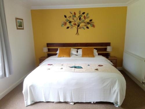 a bedroom with a large white bed with yellow walls at Bartles Lodge in Elsing