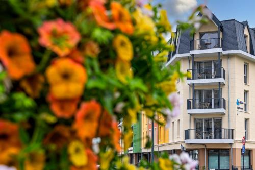 a white building with flowers in front of it at Résidence Goélia Le Phare in Le Tréport