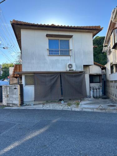 a house with a fence in front of it at Denim-yado Ken-健- in Tamano