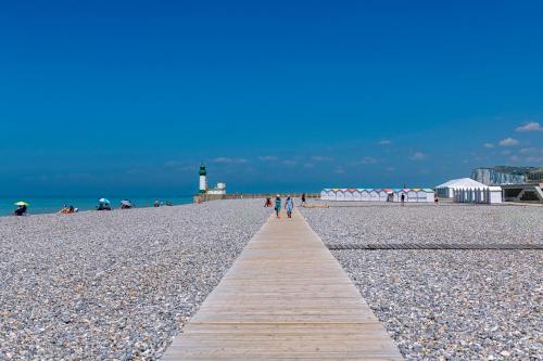 a boardwalk on a beach with a lighthouse in the background at Résidence Goélia Le Phare in Le Tréport