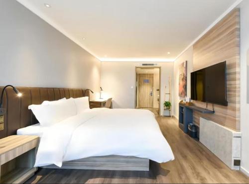 a bedroom with a white bed and a flat screen tv at Hanting Premium Hotel Beijing Daxing Jinxing Bridge Xingguang Film and Television City in Beijing