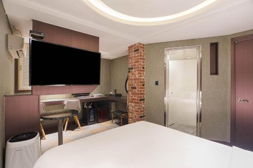 a hotel room with a bed and a tv on the wall at hotel louize in Seoul