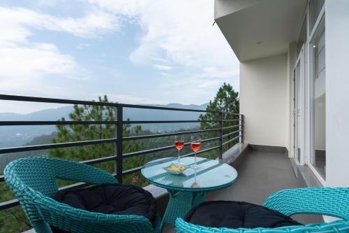 a balcony with a table and two glasses of wine at Pristine Pines by VEO - 8BR,2BR with Indoor Games at Kasauli in Kasauli
