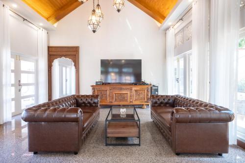 a living room with two leather couches and a television at Naka Villa at Pratumnak in Pattaya South
