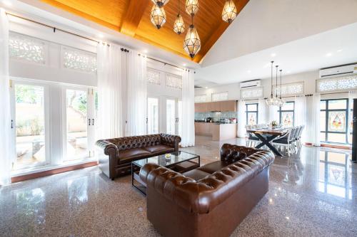 a living room with leather furniture and a kitchen at Naka Villa at Pratumnak in Pattaya South