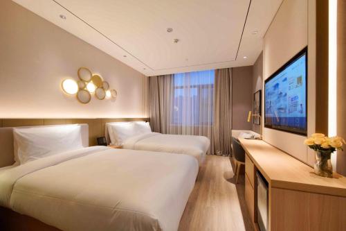 ein Hotelzimmer mit zwei Betten und einem Flachbildfernseher in der Unterkunft Orange Beijing Yanqing Badaling Great Wall Hotel in Xibozi
