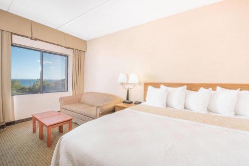 a hotel room with a bed and a chair and a window at Days Inn by Wyndham Duluth Lakewalk in Duluth