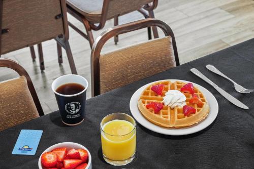a table with a plate of waffles and a glass of orange juice at Days Inn & Suites by Wyndham Winkler in Winkler