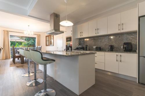 a kitchen with white cabinets and a bar with stools at Blue Outlook Garden by Atlantic Holiday in Água de Pena