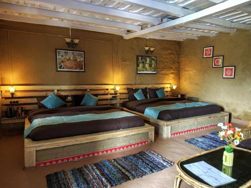a bedroom with two beds and a table and two rugs at Neelkanth Retreat in Mukteswar