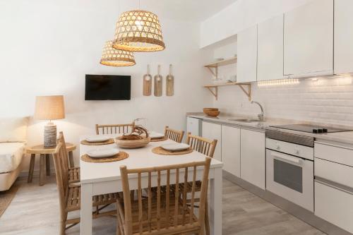 una cocina con mesa y sillas y una cocina con armarios blancos. en Mare Cheia (High Tide) Beach and Surf Apartments, en Peniche