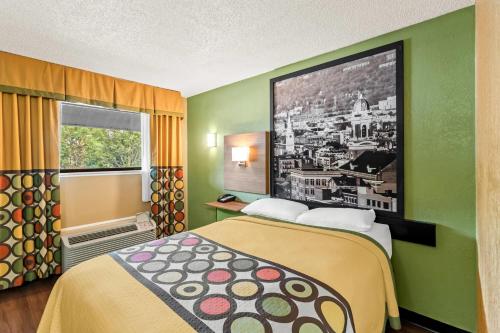a hotel room with a bed and a picture on the wall at Super 8 by Wyndham Cincinnati-Springdale OH in Springdale