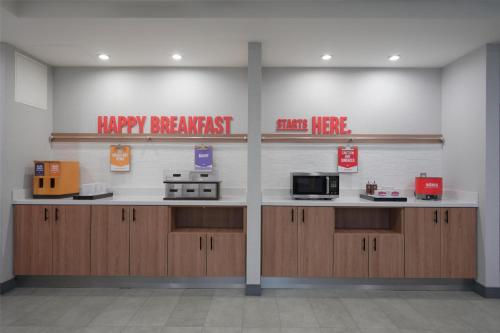 a kitchen with wooden cabinets and a sign that readshappy breakfast stop here at Hampton Inn & Suites Tulsa/Tulsa Hills in Tulsa