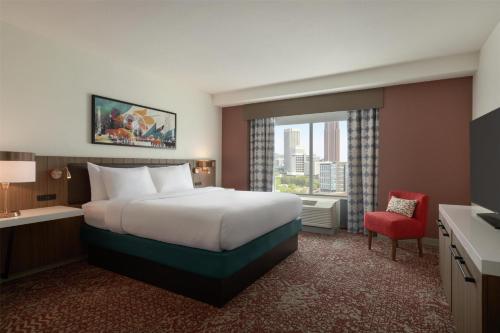 a hotel room with a large bed and a red chair at Hilton Garden Inn Atlanta Downtown in Atlanta