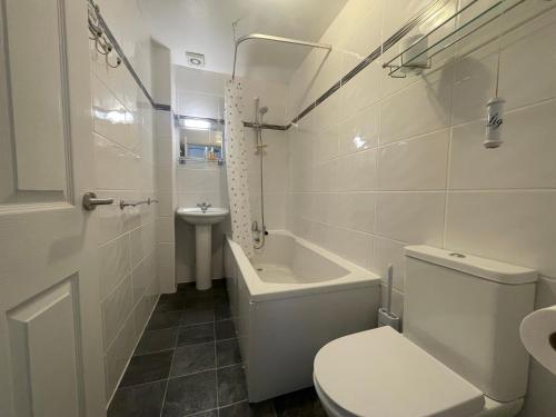 a white bathroom with a toilet and a sink at Wedgwood Hotel, North Shore Room in Llandudno