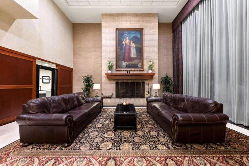 a living room with two leather couches and a fireplace at Wyndham Riverfront Hotel in Little Rock