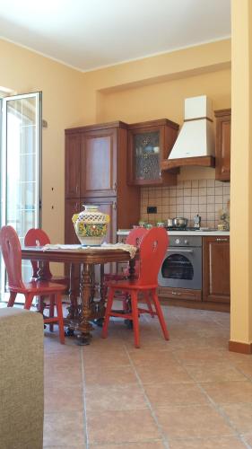 a kitchen with a table with red chairs and a kitchen with a stove at Sicily Sea House in Gioiosa Marea