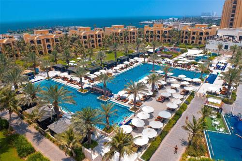 an aerial view of a resort with two pools and umbrellas at DoubleTree by Hilton Resort & Spa Marjan Island in Ras al Khaimah