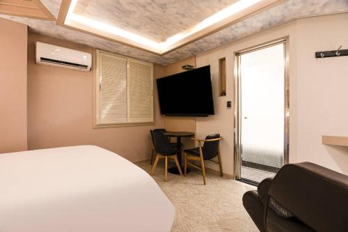 a bedroom with a bed and a table and a tv at hotel louize in Seoul