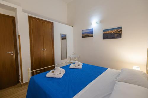 a bedroom with a blue bed with towels on it at Mare e Misteri Apartment in Trapani