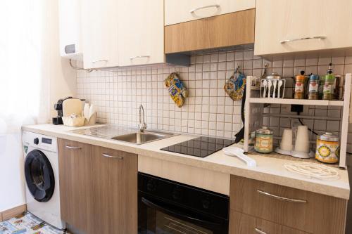 a kitchen with a sink and a washing machine at Mare e Misteri Apartment in Trapani