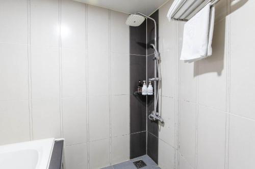 a shower in a bathroom with white tiles at hotel louize in Seoul