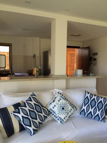 a white couch with blue and white pillows on it at Apartamento Golf Iberostate Praia do Forte in Praia do Forte