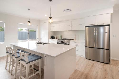a kitchen with white cabinets and a stainless steel refrigerator at Tidal Treasure Family Home B in Busselton