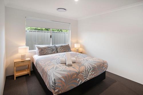 a bedroom with a bed with two lamps and a window at Tidal Treasure Family Home B in Busselton