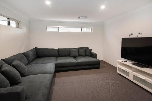 a living room with a couch and a flat screen tv at Tidal Treasure Family Home B in Busselton