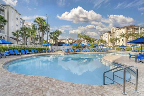 a swimming pool with blue chairs and umbrellas at Hilton Vacation Club Grande Villas Orlando in Orlando
