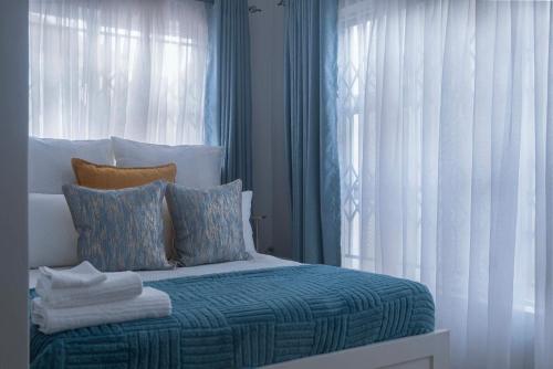 a bedroom with a bed with blue and white curtains at Siphosami Apartments - Unit 2 Mopane in Lilongwe