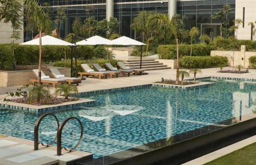 a swimming pool with chairs and umbrellas in a building at Andaz Delhi, by Hyatt in New Delhi
