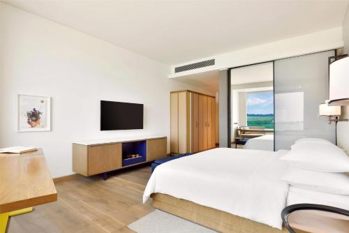 a hotel room with a bed and a tv at Andaz Delhi, by Hyatt in New Delhi