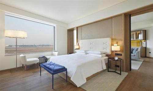 a bedroom with a large bed and a large window at Andaz Delhi, by Hyatt in New Delhi