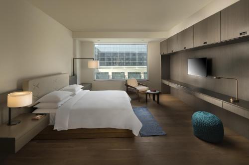 a bedroom with a white bed and a tv at Andaz Delhi, by Hyatt in New Delhi