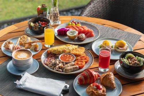 a table topped with plates of breakfast foods and drinks at Radisson Blu Bali Uluwatu in Uluwatu