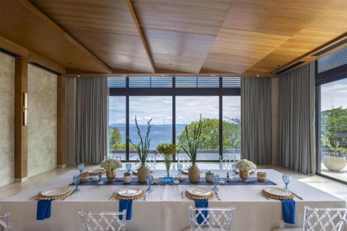 a dining room with a long table with chairs and windows at Waldorf Astoria Costa Rica Punta Cacique in Playa Hermosa