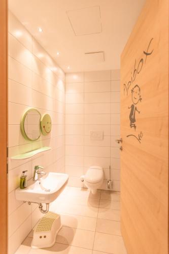 a white bathroom with a sink and a toilet at Hotel Glemmtalerhof in Saalbach Hinterglemm