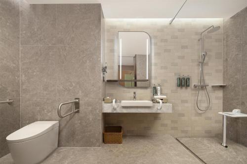 a bathroom with a sink and a toilet and a mirror at Hilton Garden Inn Urumqi Railway Station in Ürümqi