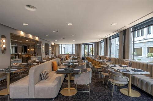 a restaurant with tables and chairs and windows at Hilton Turin Centre in Turin