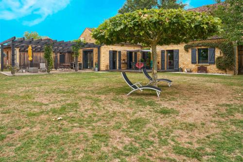 a bench under a tree in front of a house at Au Bout du Chemin - Vue Chateau in Vitrac