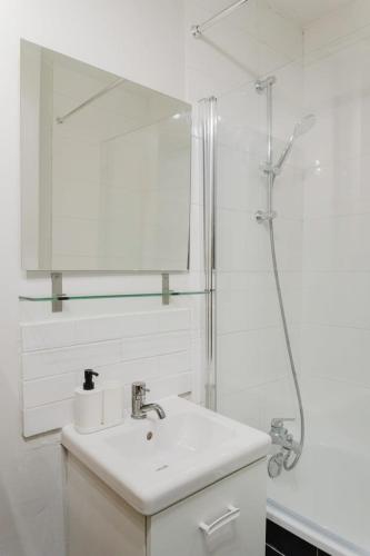 a white bathroom with a sink and a shower at La Madeleine -two bedroom apartment in La Madeleine